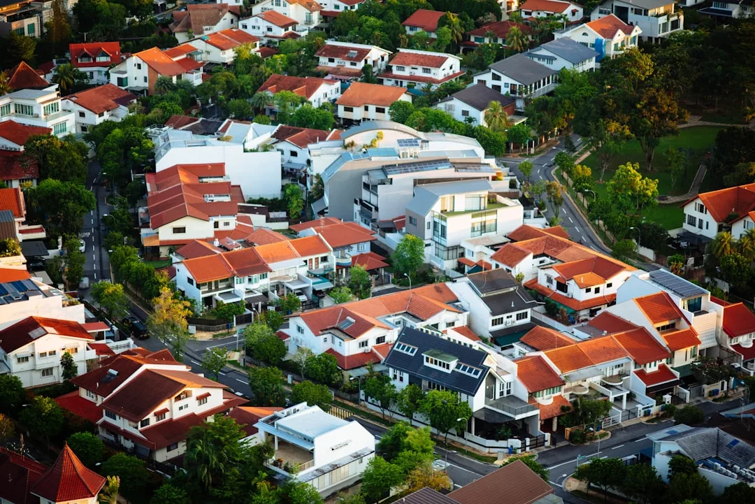 Vista aérea de un barrio residencial de Mallorca con casas de tejados rojos y naranjas, árboles verdes, calles serpenteantes y un toque de lujo.